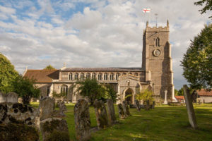 St. Mary's Church in background on sunny evening against blue sky with clouds and with leaning gravestones in foregound