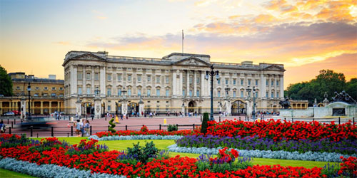 image of buckingham palace from the end of pall mall with brightly coloured planting in the beds in foreground
