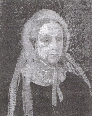 An old black and white photograph showing a portrait of a lady who has a scarf around her head and part of it hanging over her shoulders. She looks quite severe !